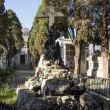 Ritorniamo sul viale principale, dove al centro si trova una grande scultura bronzea posta su un blocco di pietre poste a gradoni: si tratta della Croce con angelo dolente 
